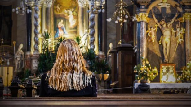 Junge Frau sitzt allein in der Kirche.