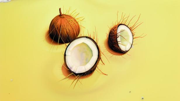 Drei Kokosnüsse liegen am Strand.