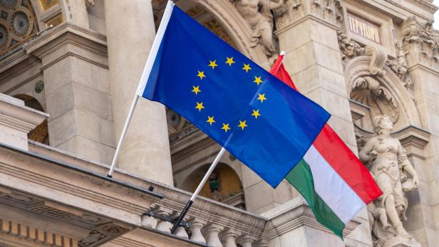 Flaggen der Europäischen Union und Ungarns wehen an Masten vor einem Gebäude im Zentrum der ungarischen Hauptstadt Budapest.