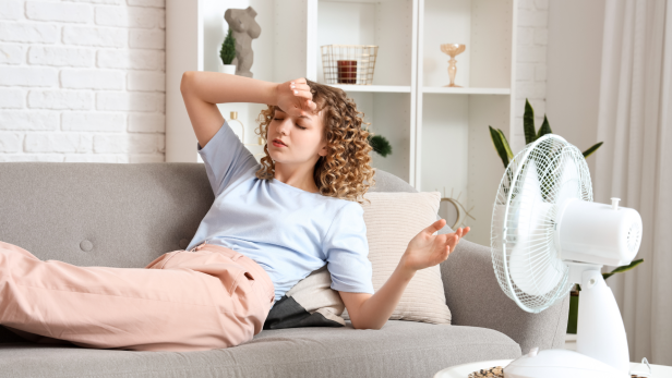 Kühle Oasen: 5 Tipps, um Räume im Sommer abzukühlen, Frau vor Ventilator.