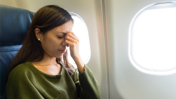 Frau sitzt ängstlich im Flugzeug, was man bei Flugangst machen sollte 
