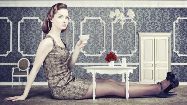 Eine Frau sitzt auf dem Boden und hält eine Teetasse in einem eleganten Raum.