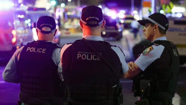Drei Polizisten der New South Wales Polizei stehen nachts auf einer Straße.