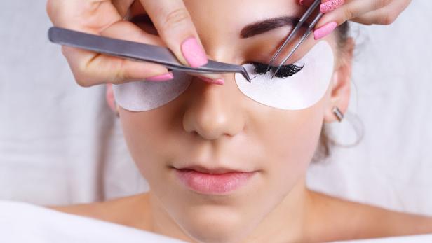 Frau lässt sich die Wimpern machen.