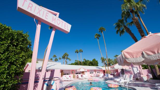 Pool und Palmen im Trixie Motel in Palm Springs, pinke Outdoormöbel, pinkes Schild mit der Aufschrift: Trixie Motel
