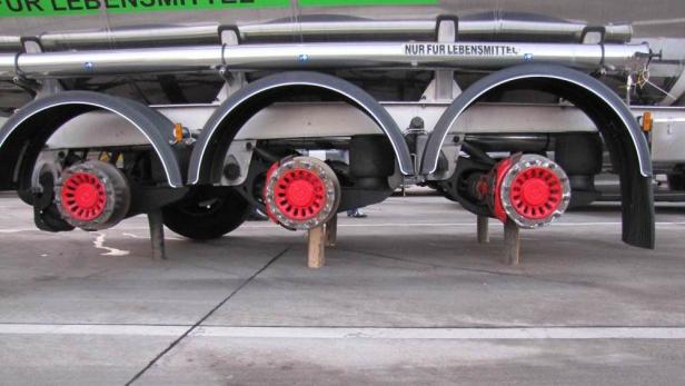 Die Hinterachse eines Tankwagens für Lebensmittel wird mit Holzkeilen abgestützt.