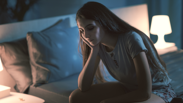 Frau sitzt nachdenklich im Bett, kann nicht schlafen, Mind after Midnight