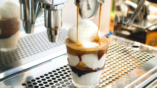 Ein Affogato wird zubereitet, wobei Espresso über eine Kugel Eis gegossen wird.
