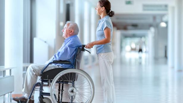 Senior man sitting on a wheelchair with caregiver