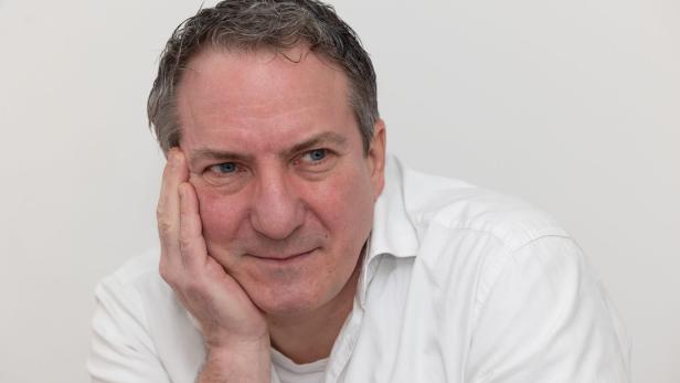 Ein Mann in einem weißen Hemd stützt sein Gesicht mit der Hand ab.