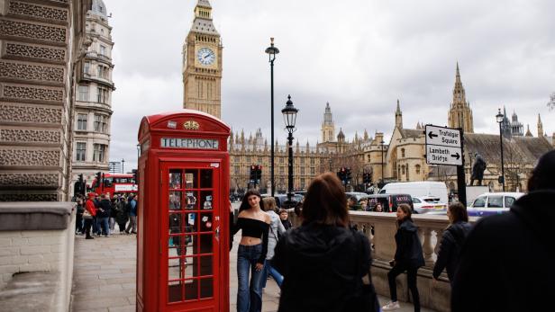 Frau posiert für ein Foto vor einer Telefonzelle in London, Big Ben im Hintergrund