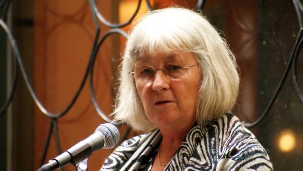Eine ältere Frau mit Brille spricht in ein Mikrofon.