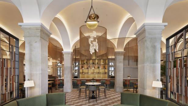 Ein elegantes Bar-Interieur mit hohen Decken, Säulen und einer auffälligen Beleuchtung über der Bar.