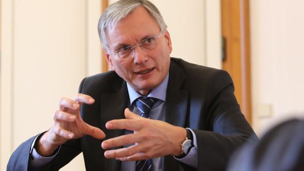 Ein Mann mit Brille und Anzug gestikuliert mit seinen Händen.