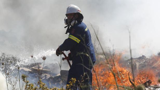 Ein Feuerwehrmann löscht einen Waldbrand südlich von Athen