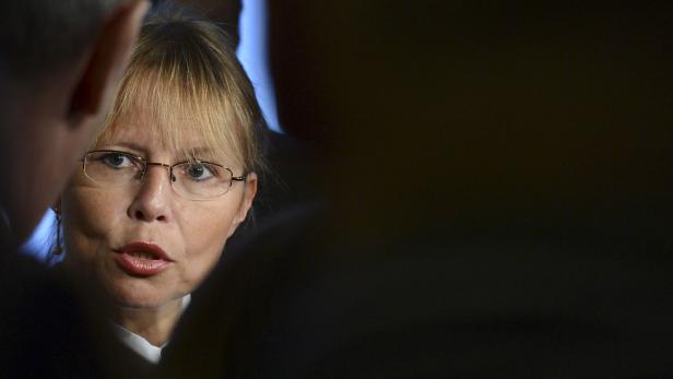 Eine Frau mit Brille spricht mit jemandem im Vordergrund.