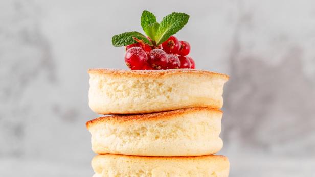 Ein Stapel Soufflé-Pfannkuchen, garniert mit roten Johannisbeeren und Minze.