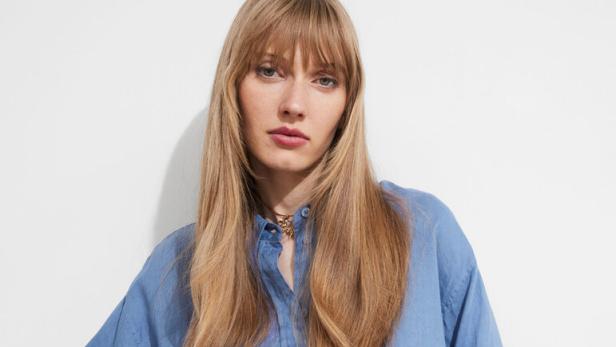 Eine Frau trägt ein blaues Hemd und gestreifte Shorts mit einem breiten Gürtel.