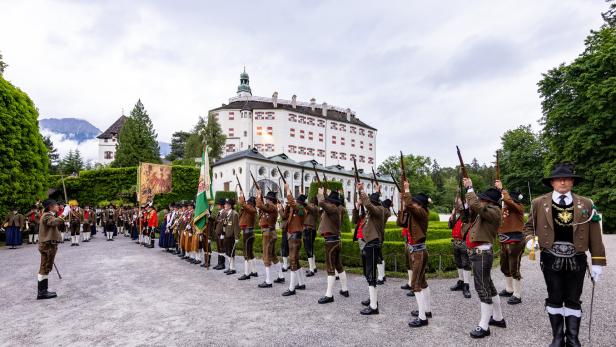Vor Schloss Ambras feuern Schützen in Tracht mit Gewehren in die Luft.