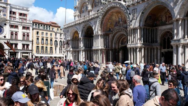 FILE PHOTO: Tourists walk in St Mark's Square on the day Venice municipality introduces a new fee for day