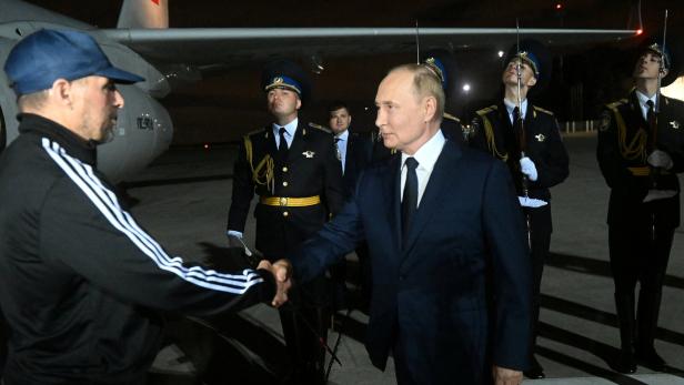 Putin begrüßt einen Mann am Flughafen