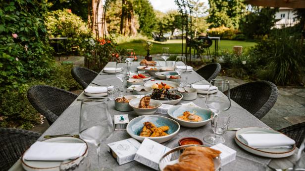 Ein gedeckter Tisch mit Speisen im Freien, Arrangement von „Salon Bökermann x The Sign“.