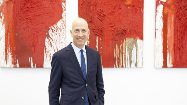 Ein Bild von Wirtschaftsminister Martin Kocher vor einem Kunstwerk.