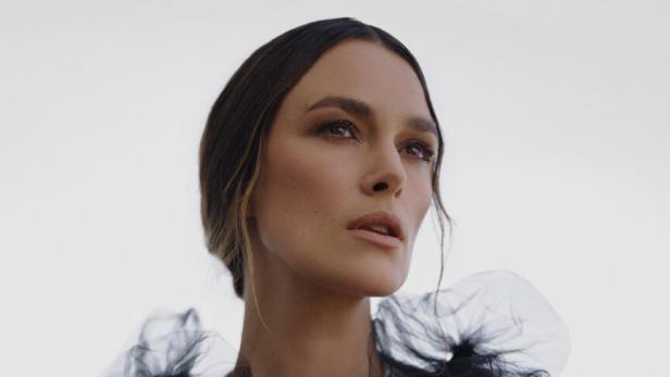 Keira Knightley trägt ein blaues Kleid und auffälligen Schmuck.