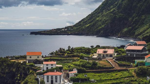 Häuser mit roten Dächern in einer grünen Landschaft auf den Azoren.