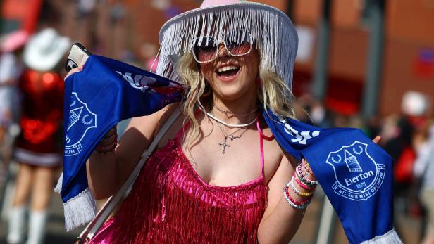 Eine lachende Frau mit einem Schal des FC Everton und einem pinkfarbenen Paillettenkleid.