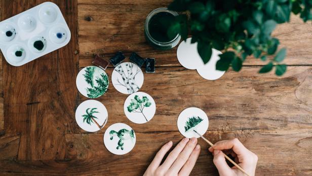 Eine Person malt kleine Landschaftsbilder mit Aquarellfarben.