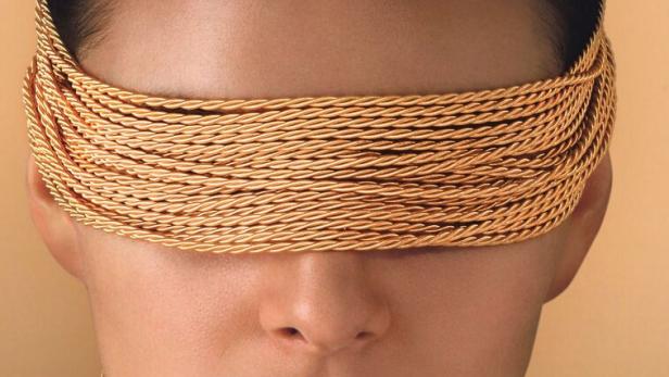 Das Gesicht einer Frau ist mit einer goldenen Wellendorff-Kordel bedeckt, die auch als Halskette dient.