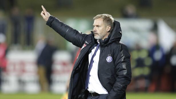 Ein Mann in einer Winterjacke zeigt mit dem Finger nach oben.