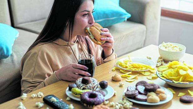 Overweight young woman eating junk food