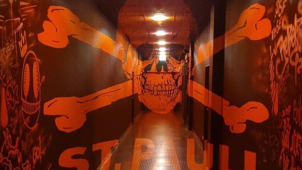 Piratenlogo des FC St. Pauli mit Totenkopf vor rotem Graffiti im Spielertunnel des Vereins