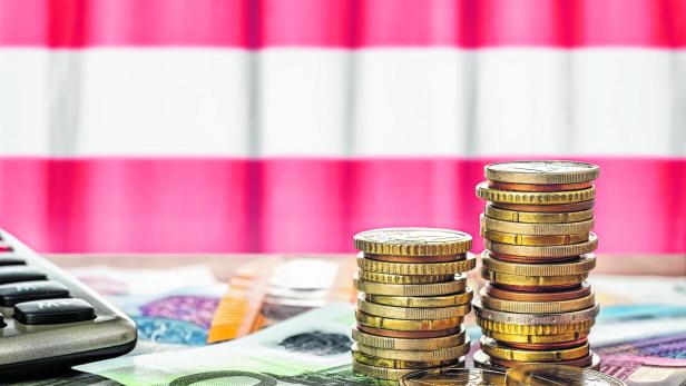 Euro banknotes and coins in front of the national flag of Austria