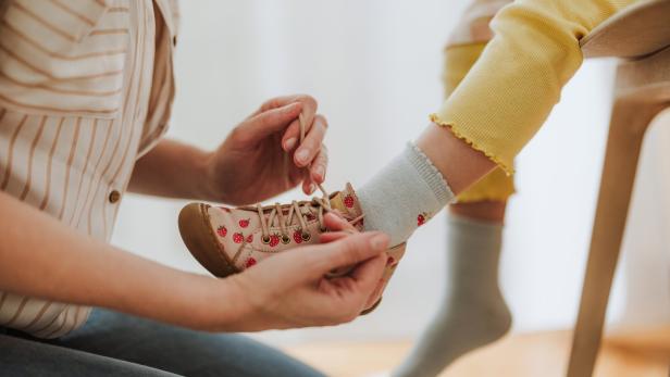 Kind bekommt Schuhe angezogen.