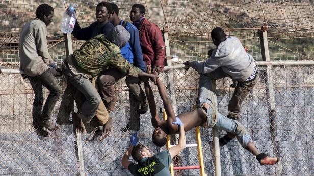 Afrikanische Migranten versuchen den Grenzzaun von Melilla zu stürmen.