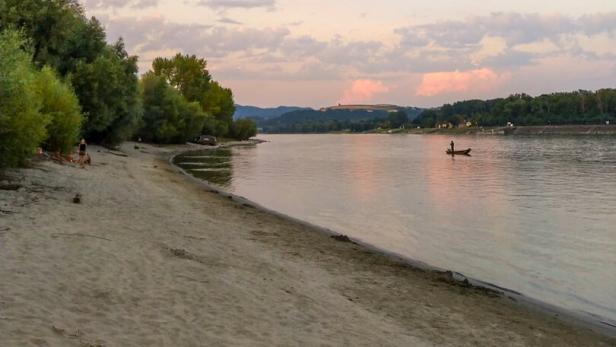 Ein Sandstrand in Luberegg mit einem kleinen Boot auf dem Fluss.