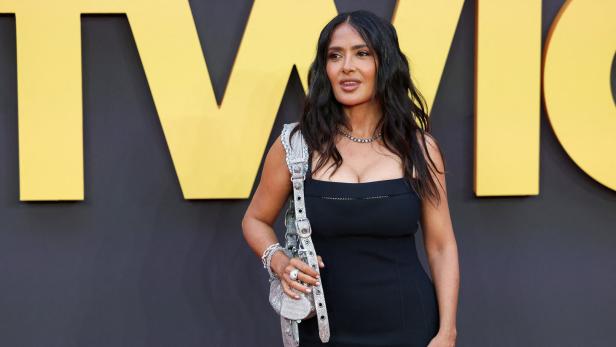 Salma Hayek trägt ein schwarzes Kleid und eine silberne Handtasche.