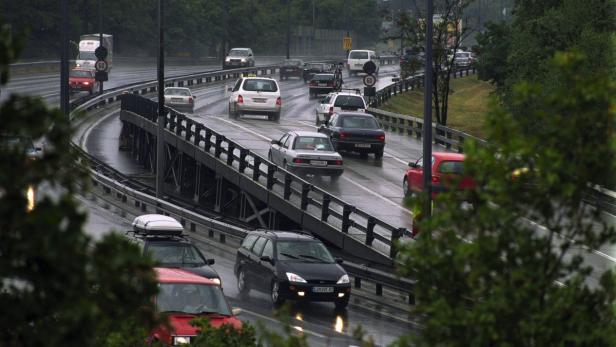 Autoverkehr auf einer regnerischen Autobahn mit einer Brücke.