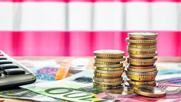 Euro banknotes and coins in front of the national flag of Austria