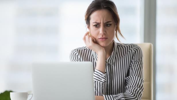 Eine Frau schaut unzufrieden auf ihren Laptop. 