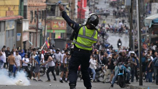 Polizist vor Demonstranten in Caracas