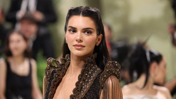 Kendall Jenner trägt ein aufwendiges, dunkles Kleid mit goldenen Verzierungen.
