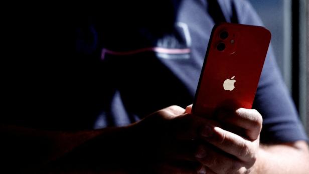 Eine Person hält ein rotes iPhone in der Hand.