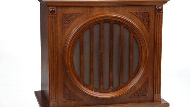 Ein antikes, hölzernes Radiogehäuse mit einem runden Lautsprechergitter.