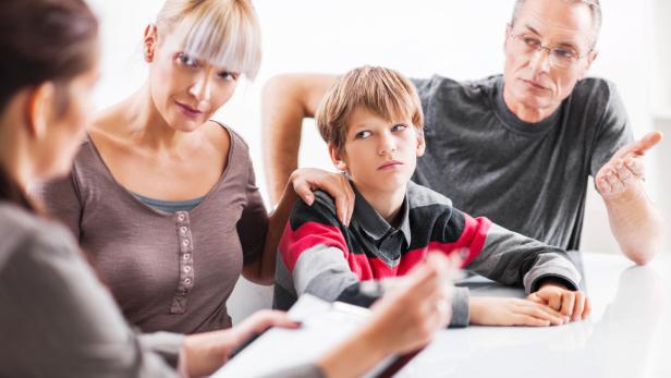 Eine Familie sitzt bei einem Gespräch mit der Lehrerin.