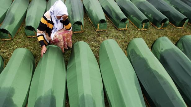 A Bosnian woman cries beside the coffin of a relat