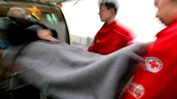 Rettungssanitäter schieben eine Patientin auf einer Trage in einen Krankenwagen.